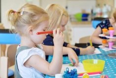 Mädchen sitzen malend an einem Tisch in der Kita