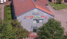 Amtsgebäude frontal von vorne/oben mit den Wappen der 7 Gemeinden, sonniges Wetter