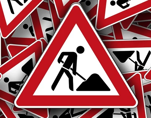 Schild Achtung Baustelle, mit diversen gleichen Schildern, durcheinander, im Hintergrund