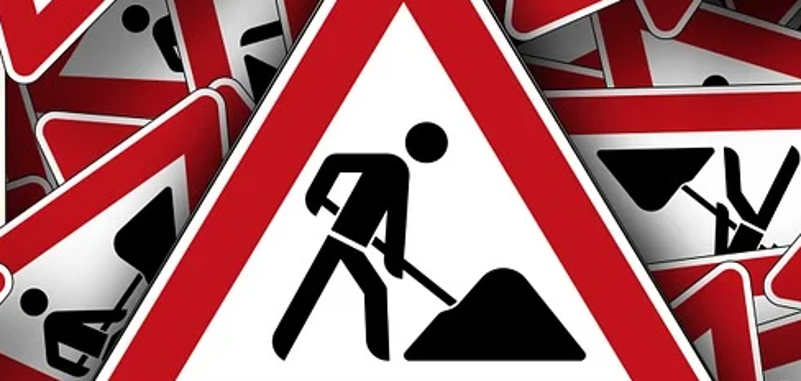 Schild Achtung Baustelle, mit diversen gleichen Schildern, durcheinander, im Hintergrund