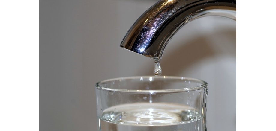 Wasserhahn tropft in Wasserglas